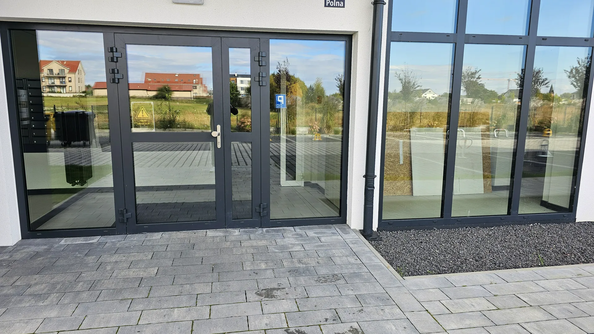 Dwuskrzydłowe drzwi wejściowe w aluminiowej czarnej ramie z przeszkloną witryną