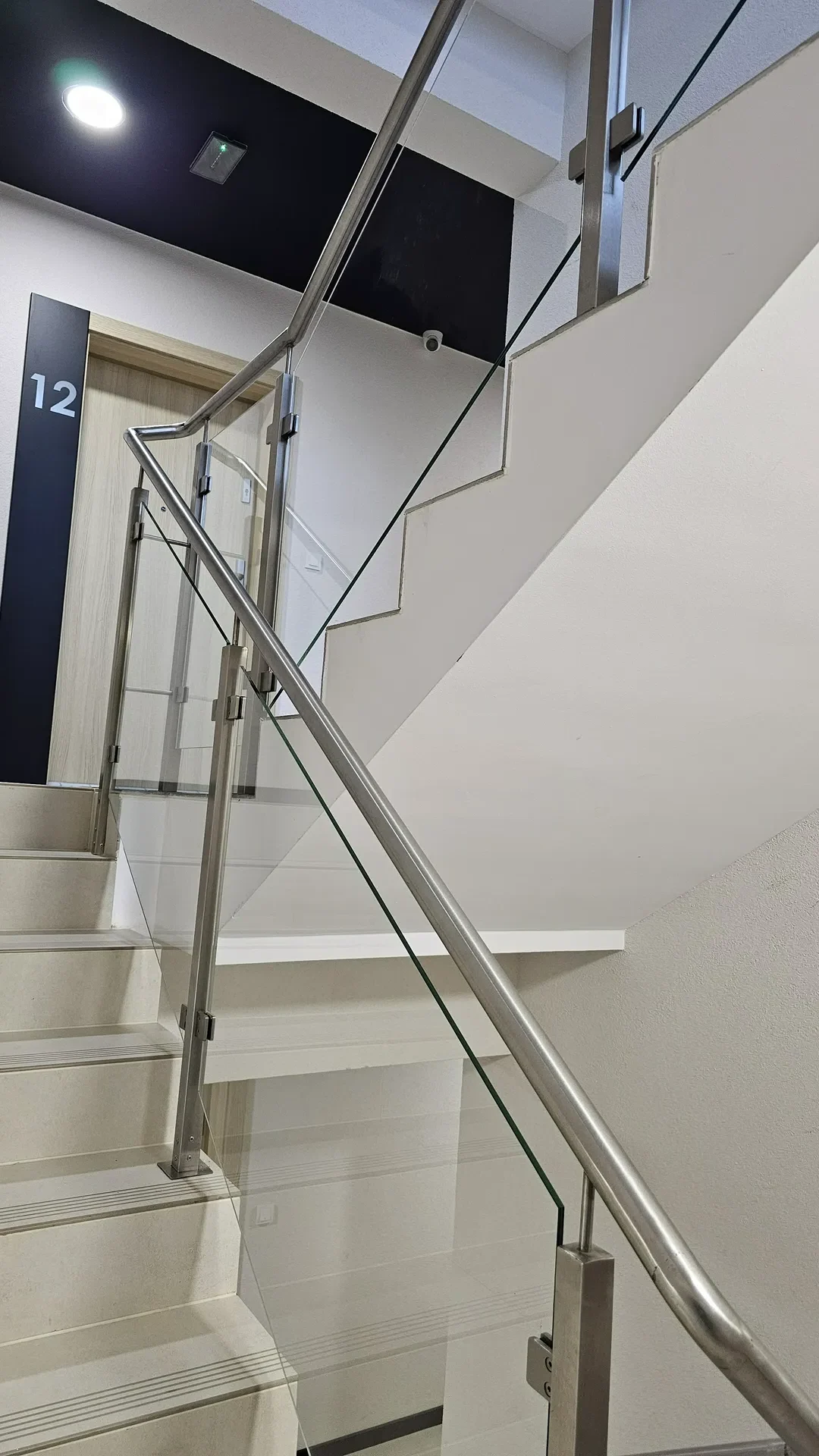 Szklana balustrada ze stali nierdzewnej i drzwi wewnątrzklatkowe na korytarzu klatki schodowej