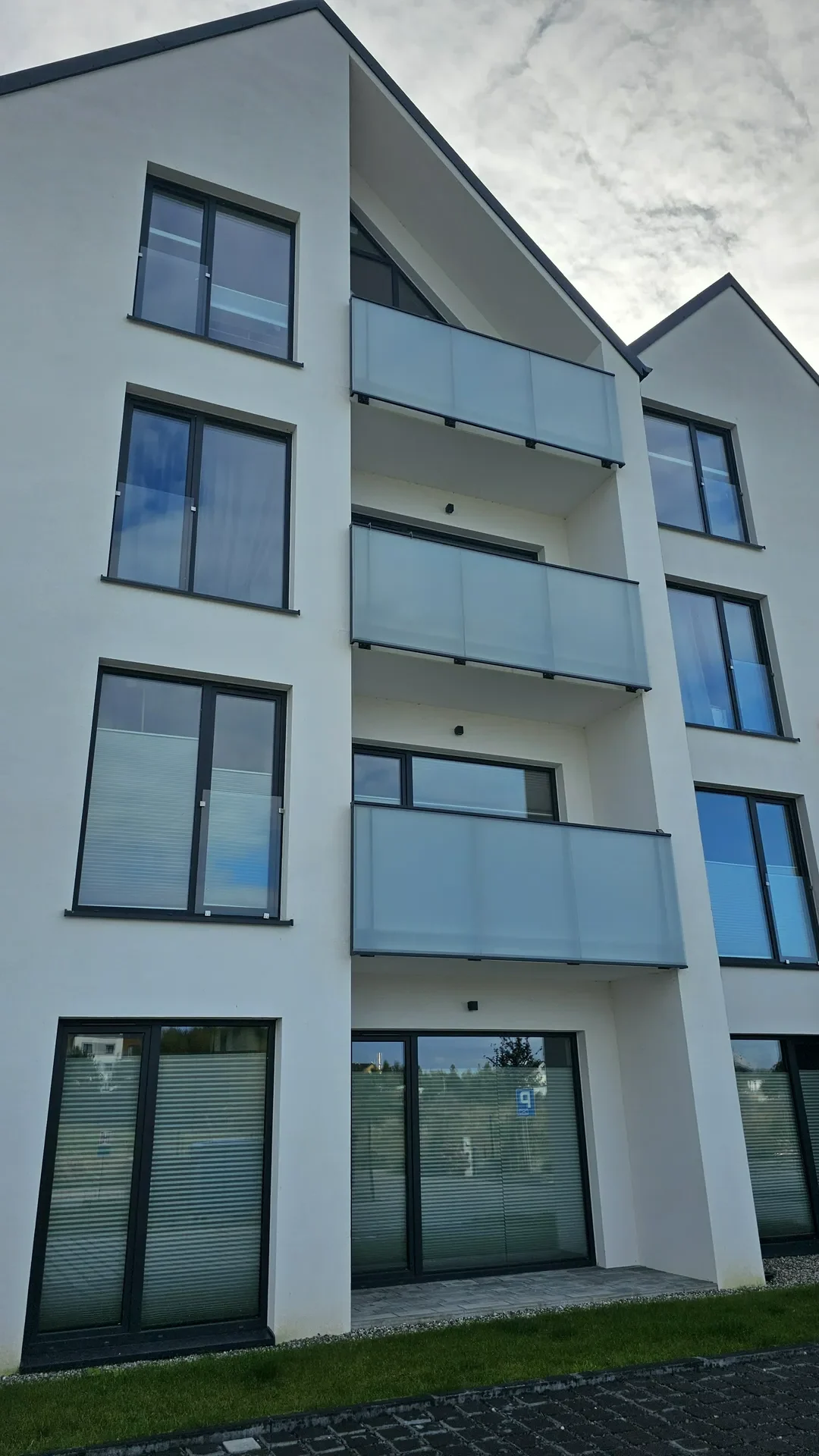 Okna aluminiowe w nowoczesnej fasadzie z przeszklonymi balustradami