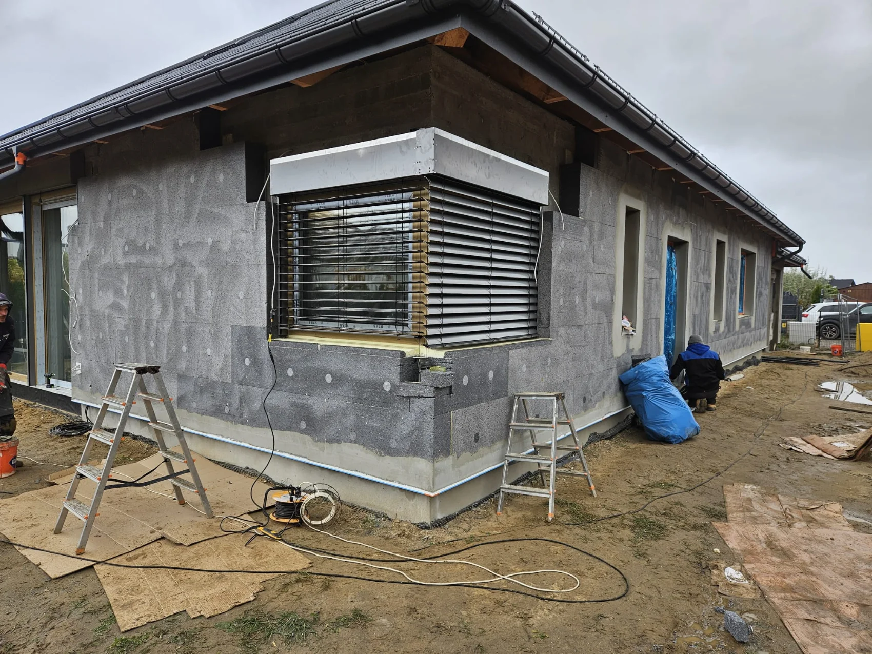 Fasada budynku w trakcie montażu zewnętrznej izolacji i zamontowanymi oknami