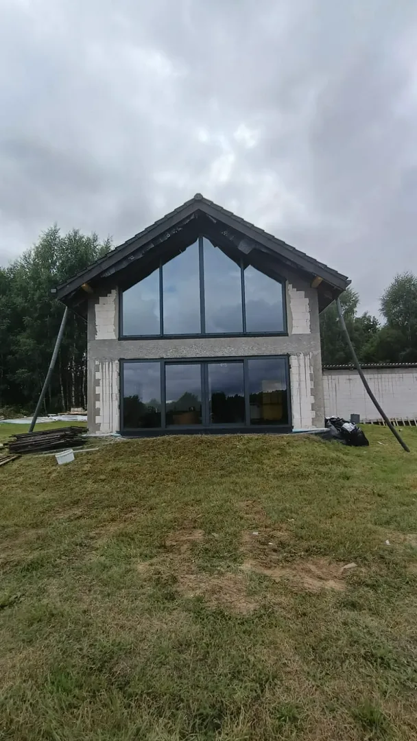 Dom z nowoczesnymi oknami wielkoformatowymi w elewacji podczas montażu