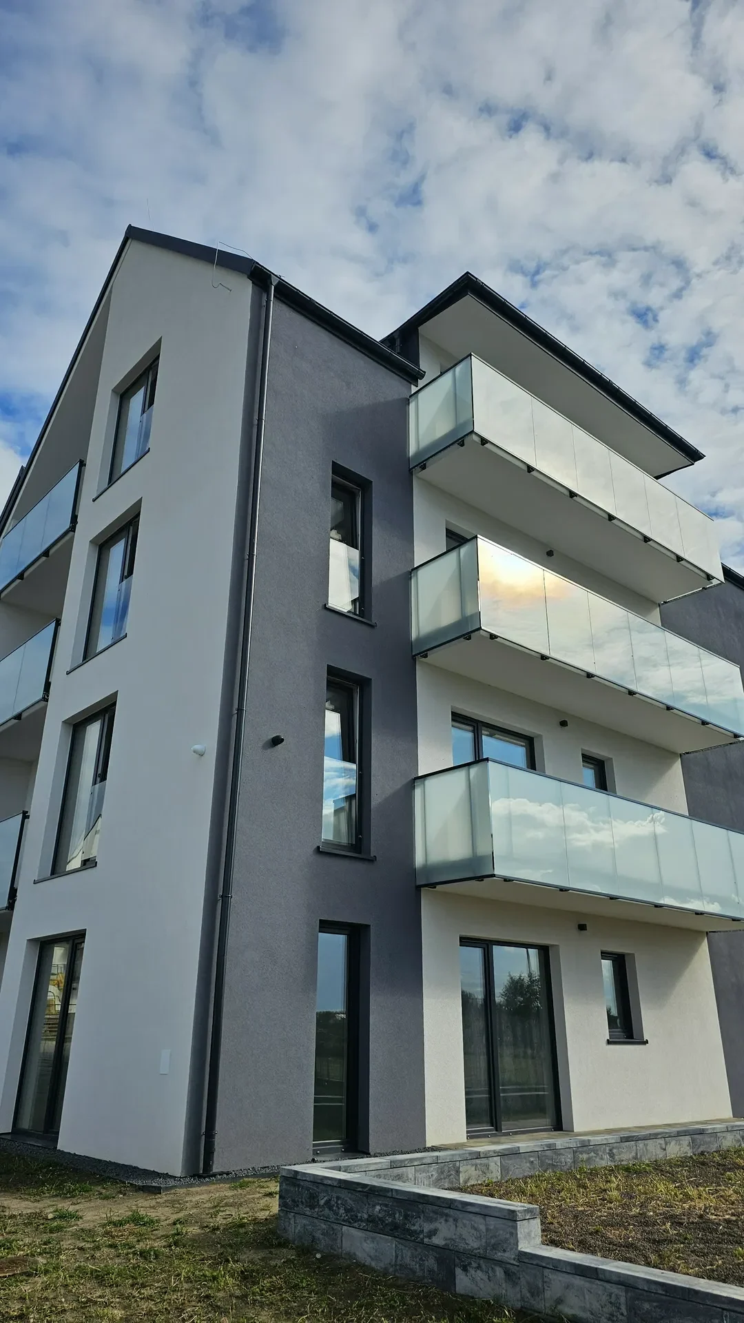 Nowoczesna fasada budynku z oknami wielkoformatowymi i szklanymi balustradami balkonów