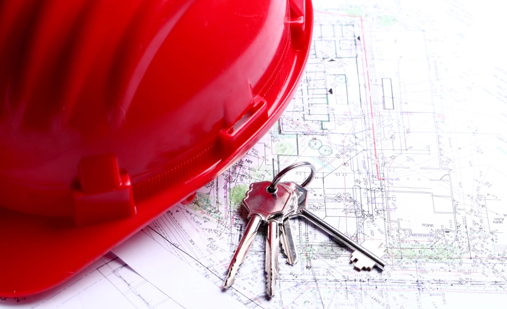 Kask ochronny i klucze na projektach architektonicznych symbolizujące montaż drzwi