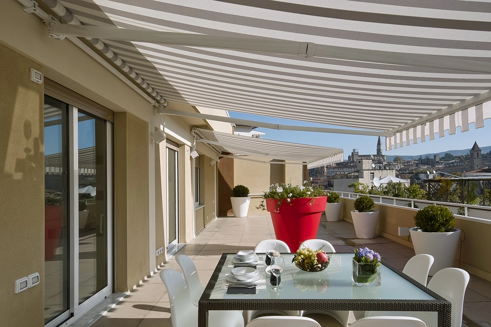 Taras z dużym stołem i markizami balkonowymi nad przeszklonymi drzwiami