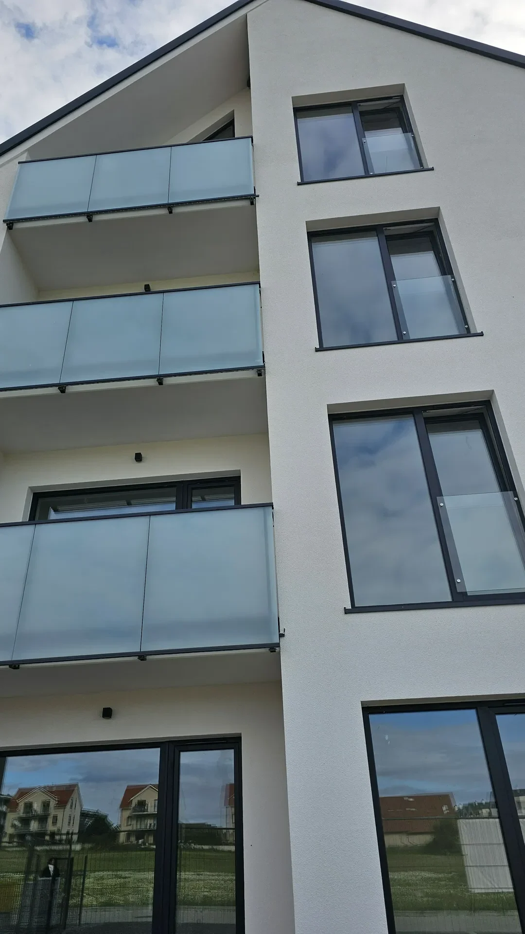 Biały budynek z oknami aluminiowymi i przeszklonymi balustradami balkonów