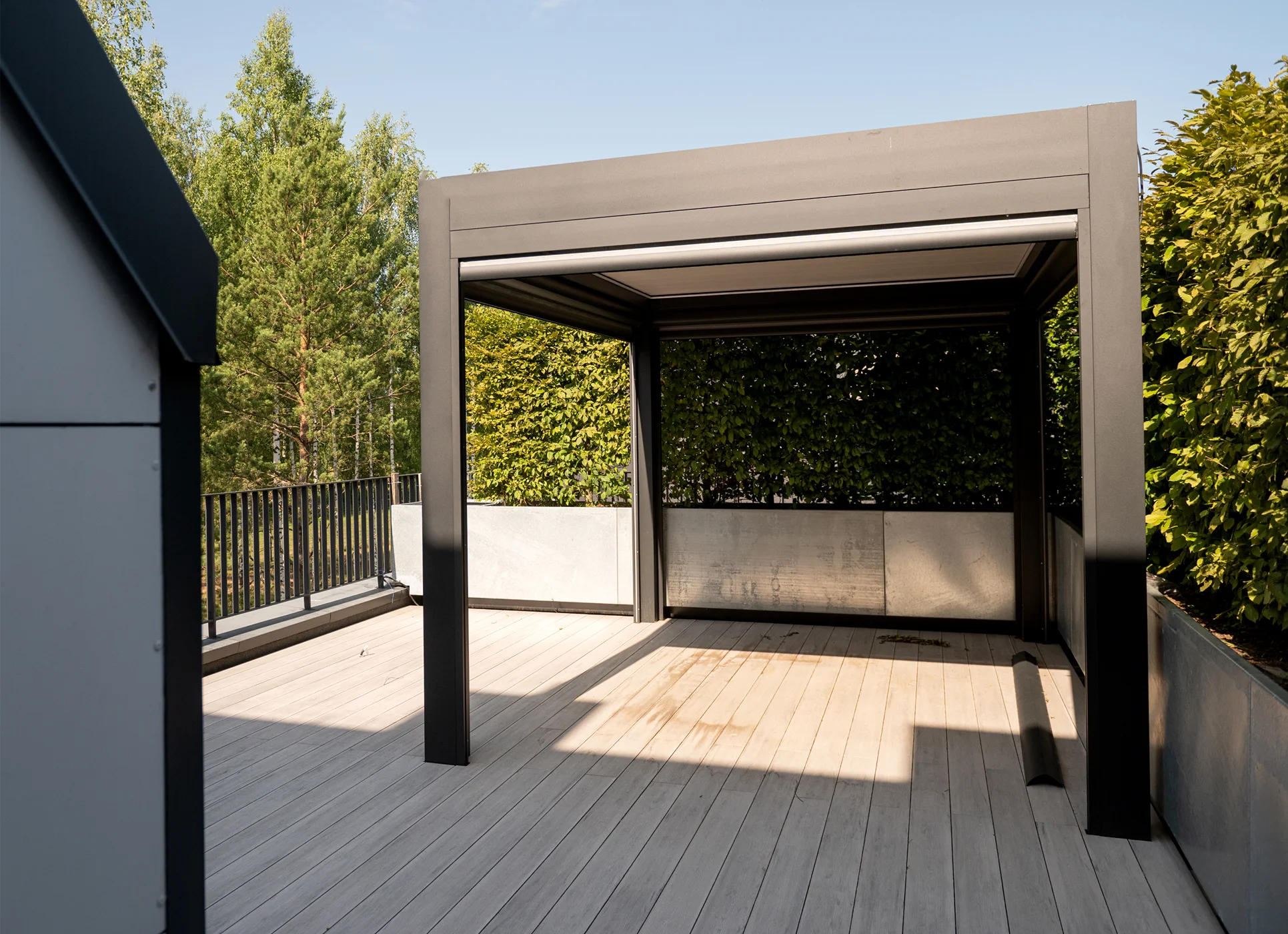 Nowoczesna aluminiowa pergola ogrodowa na drewnianym tarasie, osłona przeciwsłoneczna i struktura wsporcza