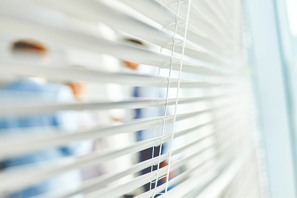 Żaluzje fasadowe w biurze z widokiem na rozmyte sylwetki osób w tle