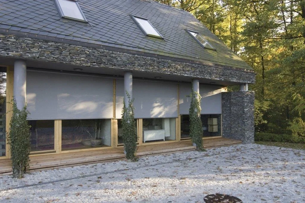 Front domu z dużymi oknami tarasowymi i opuszczonymi roletami screen