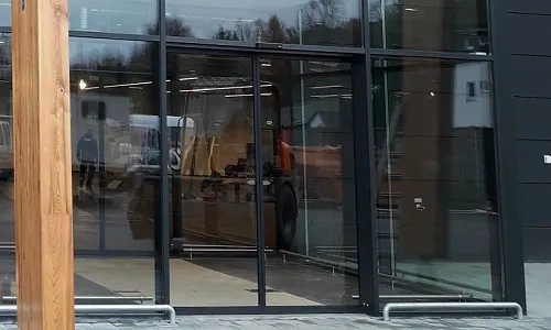 Nowoczesne witryny aluminiowe z dużymi przeszkleniami i szklanymi drzwiami wejściowymi budynku komercyjnego